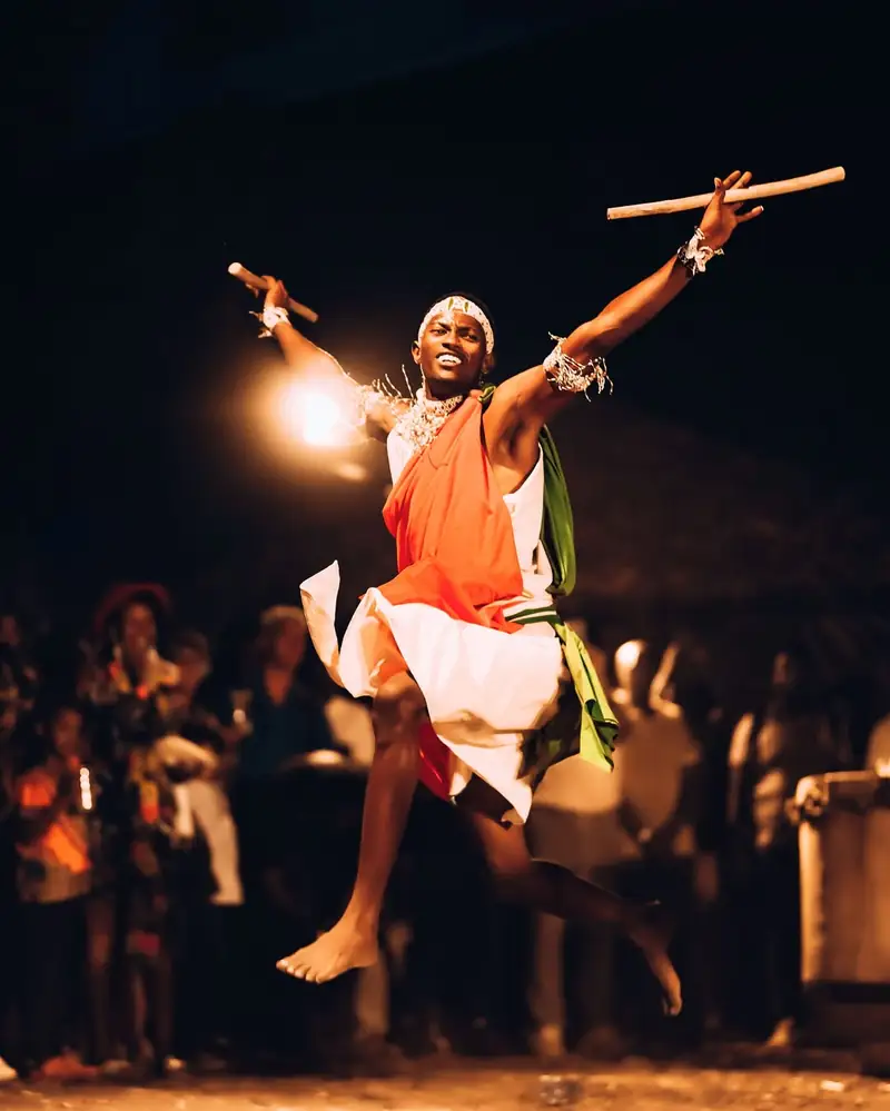 Un danseur saute, bâtons levés, devant le public de l'IZUBAFEST 2026