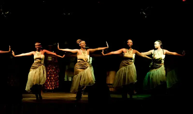 Quatre danseuses en jupes de raphia sur la scène, la nuit
