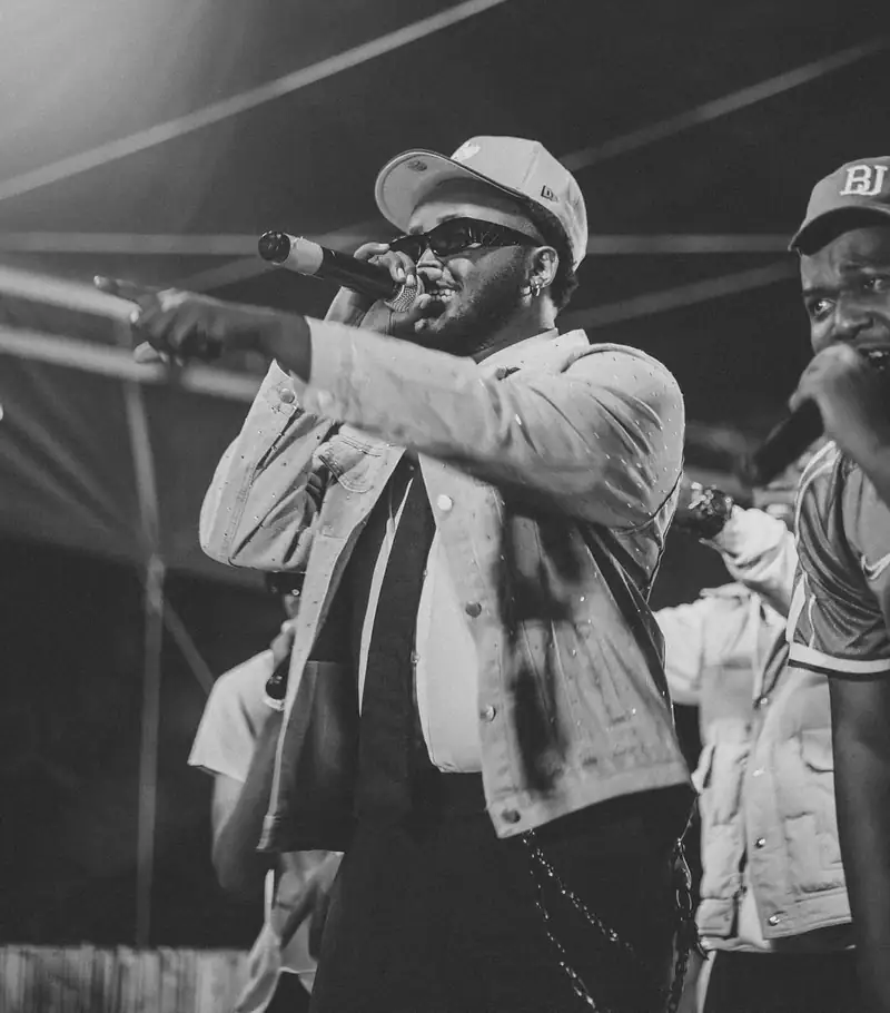 Un rappeur en casquette blanche chante au micro, photo en noir et blanc