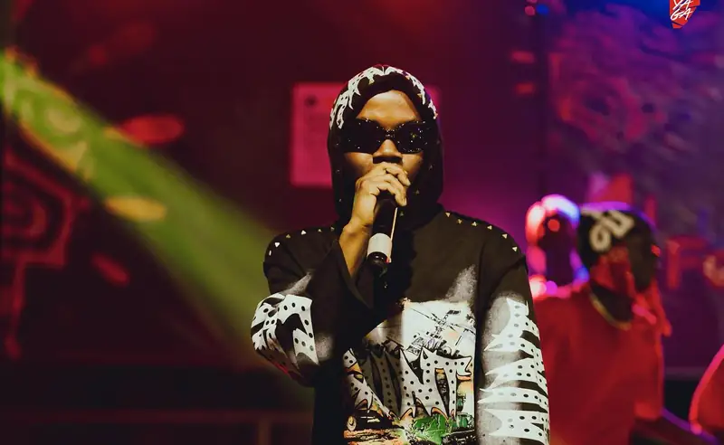 Un rappeur en lunettes de soleil chante sous les projecteurs verts