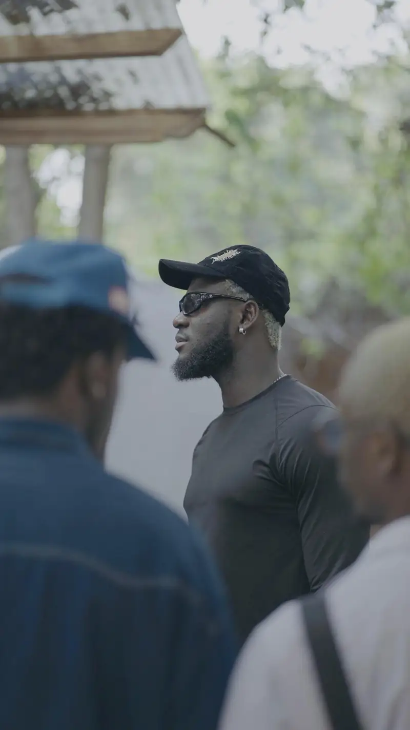 Kel-P de profil, lunettes de soleil, au milieu des artistes
