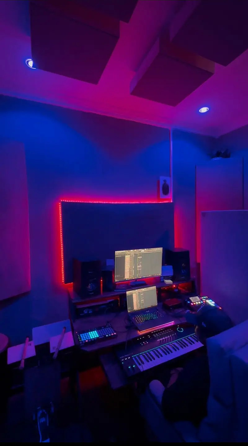 La cabine sous lumière rose et bleue, le producteur au clavier